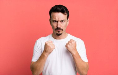 Kendinden emin, sinirli, güçlü ve agresif görünüyor. Yumrukları boks pozisyonunda dövüşmeye hazır.