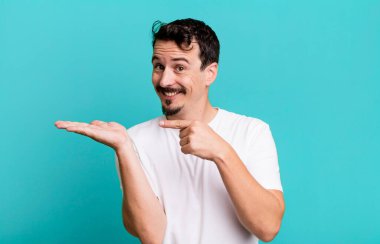 Gülümsüyor ve bir objeyi göstererek veya reklamını yaparak avucunun içindeki kopyalama alanını işaret ediyor.