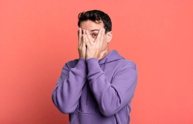 Yüzü ellerle kaplamak, parmaklarının arasından bakmak şaşırmış bir ifadeyle yan tarafa bakmak.