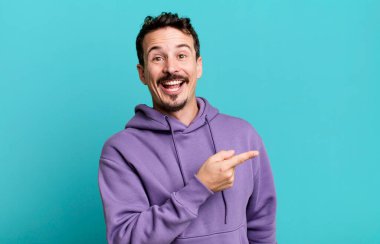 Heyecanlı ve şaşırmış görünüyor. Yana ve yukarıya bakıyor. Boşluğu kopyalıyor.