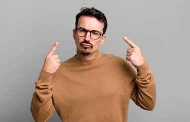 Kibirli ve agresif görünen, yukarıyı gösteren ya da ellerinle alay eden bir tavır takınarak.