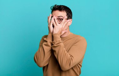 Korkuyor ya da utanıyor, dikizliyor ya da ellerle yarı kapalı gözlerle gözetliyor.