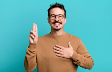 Mutlu, kendinden emin ve güvenilir görünüyor, gülümsüyor ve olumlu bir tavırla zafer işareti gösteriyor.