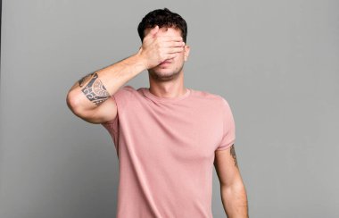 Tek eliyle gözlerini kapayan bir adam korkmuş ya da endişeli, merak ediyor ya da körü körüne bir sürpriz bekliyor.