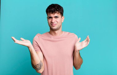 Adam şaşkın, kafası karışmış ve stresli görünüyor. Farklı seçenekler arasında merak ediyor. Belirsiz hissediyor.