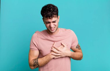 Üzgün, yaralı ve kalbi kırık bir adam, iki elini de kalbe yakın tutuyor, ağlıyor ve depresif hissediyor.