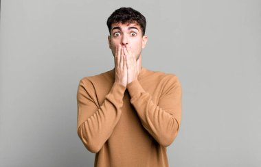 Adam mutlu ve heyecanlı, şaşırmış ve şaşırmış elleriyle ağzını kapatmış, sevimli bir ifadeyle kıkırdıyor.