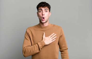 Şok olmuş ve şaşırmış hisseden, gülümseyen, el ele tutuşan, mutlu olan ya da minnettarlık gösteren bir adam.