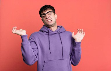 man shrugging with a dumb, crazy, confused, puzzled expression, feeling annoyed and clueless