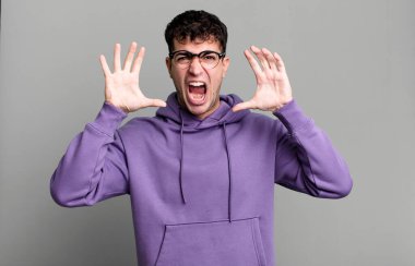 Panik ya da öfke içinde bağıran adam, şok olmuş, korkmuş ya da öfkeli, elleri başının yanında.