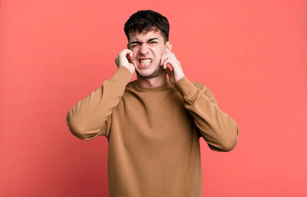 Mężczyzna Wygląda Wściekłego Zestresowanego Zirytowanego Zakrywając Uszy Ogłuszającym Dźwiękiem Dźwiękiem — Zdjęcie stockowe