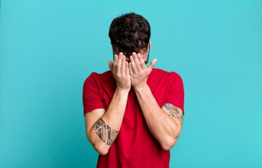 Üzgün, hayal kırıklığına uğramış, gergin ve depresif, iki eliyle yüzünü kaplayan, ağlayan