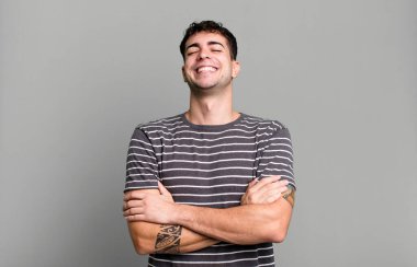 Kollarını kavuşturup mutlu bir şekilde gülüyorlar, rahat, olumlu ve tatmin edici bir pozla.