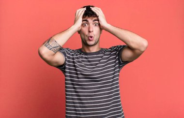 Heyecanlı ve şaşırmış görünüyor, ağzı açık, elleri başının üstünde, şanslı bir kazanan gibi hissediyor.