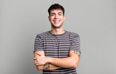 Mutlu, gururlu ve tatmin olmuş kollarını kavuşturarak gülümseyen biri gibi görünüyorsun.