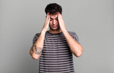 Stresli ve hayal kırıklığına uğramış görünüyor, baskı altında çalışıyor, baş ağrısı ve sorunlarla boğuşuyor.