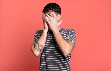 Korkuyor ya da utanıyor, dikizliyor ya da ellerle yarı kapalı gözlerle gözetliyor.