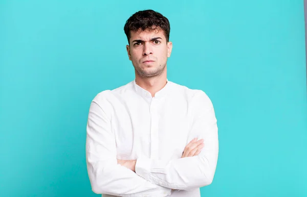 man feeling displeased and disappointed, looking serious, annoyed and angry with crossed arms