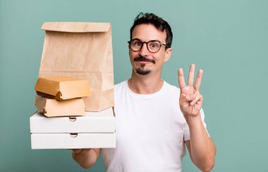 adult man smiling and looking friendly, showing number three. fast food delivery and take away concept