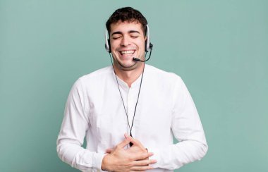 Yetişkin bir adam kulaklıkla komik bir şakaya yüksek sesle gülüyor. tele pazarlamacı konsepti