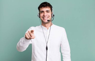 Yetişkin bir adam kamerayı işaret ederek seni kulaklıkla seçiyor. tele pazarlamacı konsepti