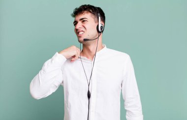 Yetişkin bir adam stresli, endişeli, yorgun ve kulaklıkla hayal kırıklığına uğramış hissediyor. tele pazarlamacı konsepti