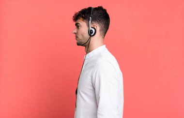 Yetişkin bir adam profil görüşünde, kulaklıkla düşünüyor, hayal ediyor ya da hayal kuruyor. tele pazarlamacı konsepti