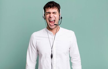 Yetişkin bir adam agresif bir şekilde bağırıyor, kulaklıkla çok sinirli görünüyor. tele pazarlamacı konsepti