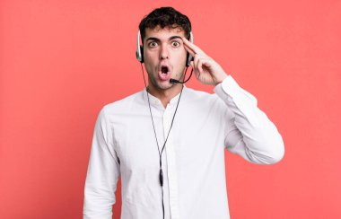 Yetişkin bir adam şaşırmış görünüyor, kulaklıkla yeni bir düşünce, fikir ya da konsept fark ediyor. tele pazarlamacı konsepti