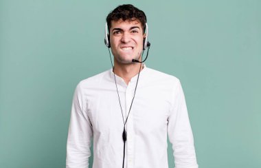 Yetişkin adam şaşkın ve kulaklıkla kafası karışmış görünüyor. tele pazarlamacı konsepti