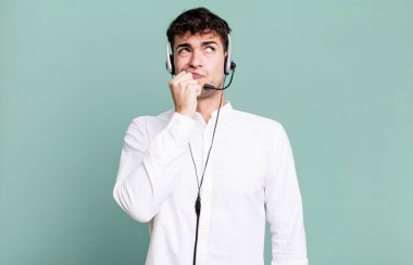 Yetişkin adam düşünüyor, kuşkulu hissediyor ve kulaklıkla karıştırıyor. tele pazarlamacı konsepti