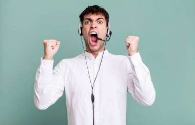 Yetişkin bir adam öfkeli bir ifadeyle kulaklıkla agresif bir şekilde bağırıyor. tele pazarlamacı konsepti