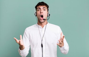 Yetişkin bir adam son derece şok olmuş ve kulaklıkla şaşırmış hissediyor. tele pazarlamacı konsepti