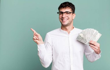 Yetişkin bir adam neşeyle gülümser, mutlu hisseder ve bir tarafı işaret eder. Dolar banknotları konsepti