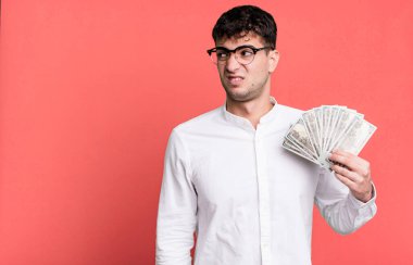 Yetişkin bir adam üzgün, üzgün ya da kızgın hisseder ve yana bakar. Dolar banknotları konsepti