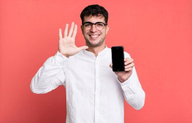 Yetişkin adam gülümsüyor ve arkadaş canlısı görünüyor, 5 numarayı gösteriyor ve akıllı telefon ekranını gösteriyor.