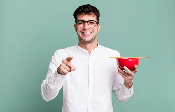 adult man pointing at camera choosing you holding a ramen noodles bowl