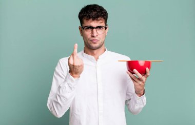 Yetişkin bir adam öfkeli, sinirli, asi ve agresif bir şekilde elinde erişte kasesi tutuyor.