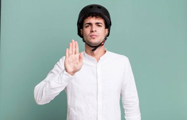 Yetişkin adam ciddi görünüyor. Avuç içi gösteriyor. Durma hareketi yapıyor. şehir motosiklet sürücüsü konsepti