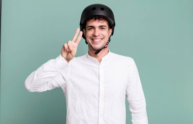 Yetişkin adam gülümsüyor ve arkadaş canlısı görünüyor, iki numarayı gösteriyor. şehir motosiklet sürücüsü konsepti