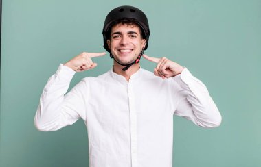 Yetişkin bir adam kendi gülüşünü işaret ederek güvenle gülümsüyor. şehir motosiklet sürücüsü konsepti