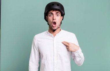 Şok olmuş ve ağzı açık, kendini işaret eden yetişkin bir adam. şehir motosiklet sürücüsü konsepti