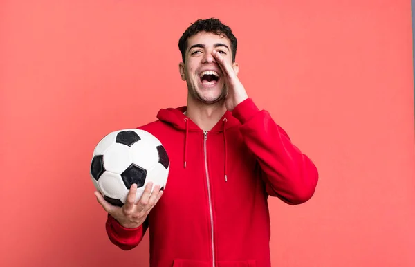adult man feeling happy,giving a big shout out with hands next to mouth. soccer and sport concept