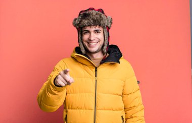 Yetişkin bir adam kamerayı işaret ederek seni anorak giyerken seçiyor. kış ve soğuk konsept