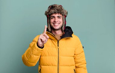 Yetişkin bir adam gururla ve kendinden emin bir şekilde anorak giyerek bir numara oluyor. kış ve soğuk konsept