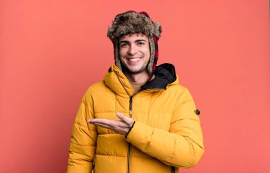 Yetişkin bir adam neşeyle gülümser, mutlu hisseder ve anorak giyerek bir konsept gösterir. kış ve soğuk konsept