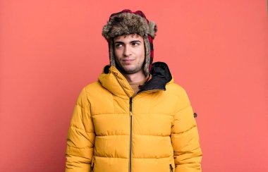 Yetişkin bir adam üzgün, üzgün ya da kızgın ve anorak giyip yan tarafa bakıyor. kış ve soğuk konsept