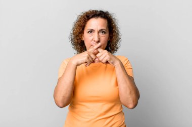 Orta yaşlı Latin bir kadın ciddi görünüyor ve iki parmağının önde olmasını istemiyor. Sessizlik istiyor.