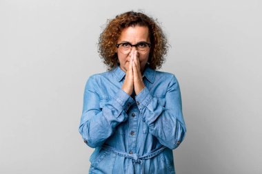 Orta yaşlı İspanyol bir kadın endişeli, umutlu ve dindar hissediyor. Avuçlarına bastırılmış, af dileyen sadık bir şekilde dua ediyor.