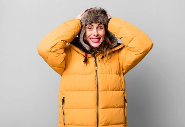hispanic pretty woman feeling stressed, anxious or scared, with hands on head. wearing an anorak. cold and winter concept